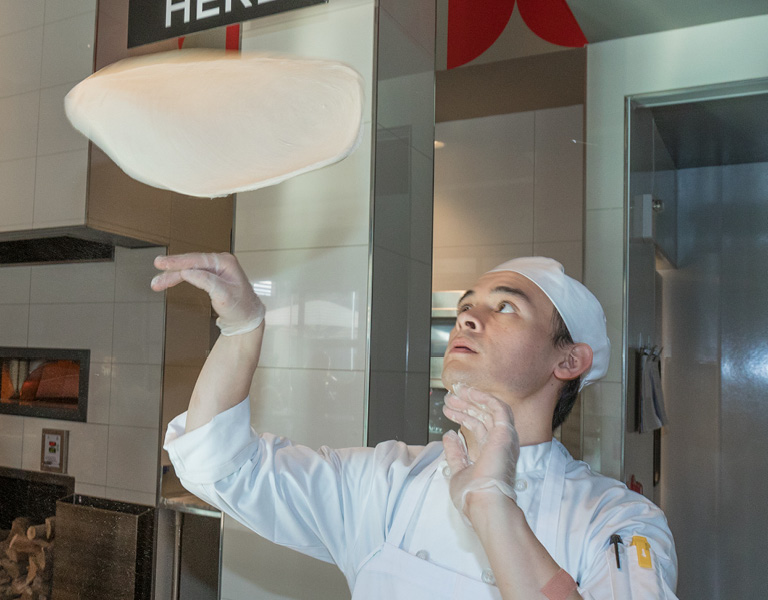 Chef tosses pizza dough in the air at Napolini in Anaheim, CA
